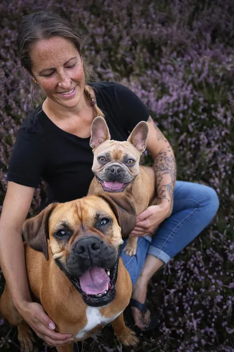 Gwens Mensch sitzt mit zwei Hunden in der Heide