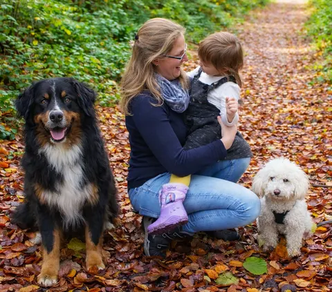 Max mit seiner Familie und einem kleinen weißen Hund im Herbstlaub